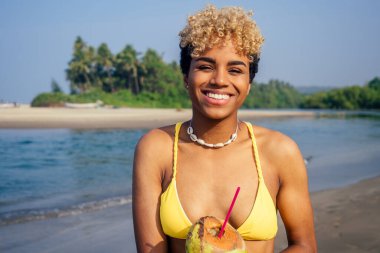 Latin kökenli güzel kadın boynunda hindistan cevizi suyu içiyor.