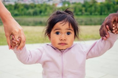 Uluslar arası Afrikalı baba parkta daireler çiziyor melez bir kız bebek.
