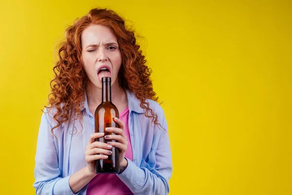 Encaracolado ruiva mulher gengibre beber cerveja e sentir mau humor em csudio fundo amarelo — Fotografia de Stock