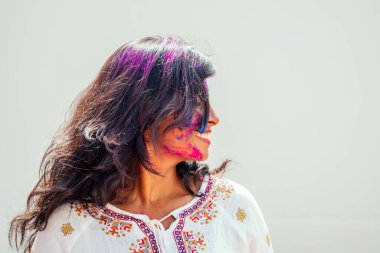 Holi Renk Festivali. Holi renginde mutlu Hintli kız portresi. Beyaz Duvar stüdyosunda dans ediyor ve eğleniyor.