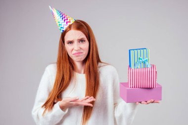 Hayal kırıklığına uğramış kızıl saçlı, tatminsiz, üzgün, kep boynuzu takmış bir kadın. Elinde stüdyo beyaz arka planda bir sürü hediye kutusu var. Yaşlanmayı kutlamaktan hoşlanmıyor.