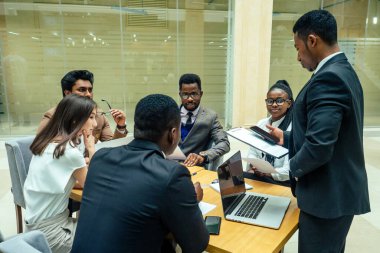 Uluslararası iş ortaklarından oluşan takım çalışması: Hintli, Koreli, Afro-Amerikalı insanlar modern odada birlikte çalışıyorlar.