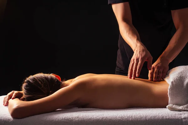 Masajista manos haciendo masaje de espalda al cliente en el centro de spa en habitación oscura — Foto de Stock