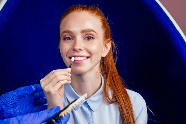 Tandläkare matchande tänder färg vackra röda hår ingefära kvinna med palett på klinik, tänder vitare koncept — Stockfoto