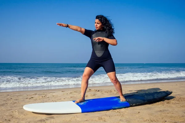 Istruttrice indiana che dimostra come alzarsi in piedi sulla tavola da surf in classe surf nel mare di Goa — Foto Stock