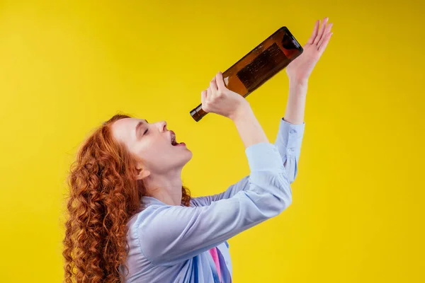 Encaracolado ruiva mulher gengibre beber cerveja e sentir mau humor em csudio fundo amarelo — Fotografia de Stock