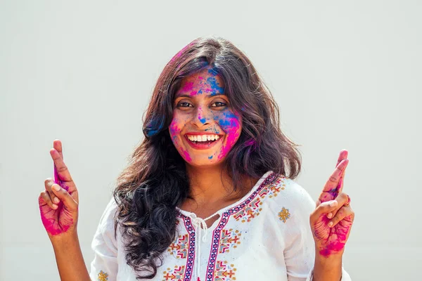 Holi Festival of Colours. Porträtt av glad indian flicka i holi color.her fingrar korsas gör en önskan — Stockfoto