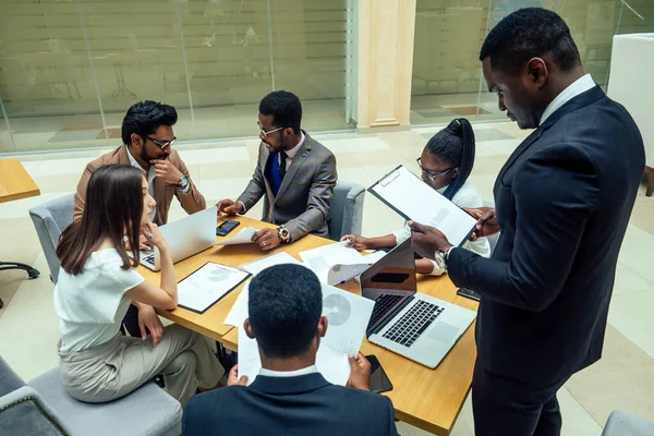 Homens afro-americanos de negócios bem vestidos fazendo um relatório para funcionários subordinados em um escritório moderno — Fotografia de Stock