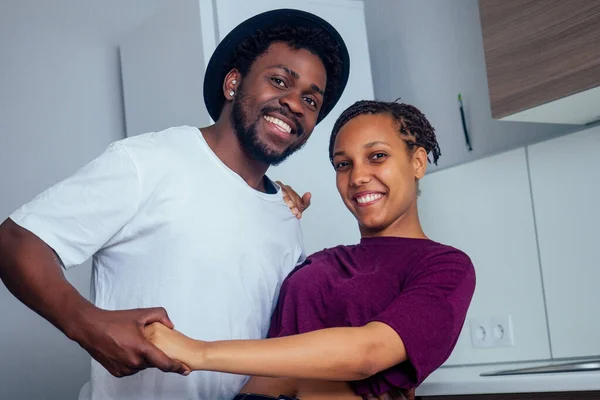 Hermosa pareja afroamericana joven está sonriendo mientras baila en la cocina — Foto de Stock