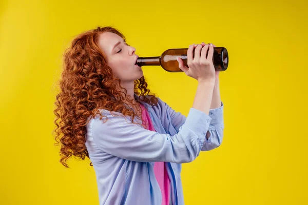 Encaracolado ruiva mulher gengibre beber cerveja e sentir mau humor em csudio fundo amarelo — Fotografia de Stock