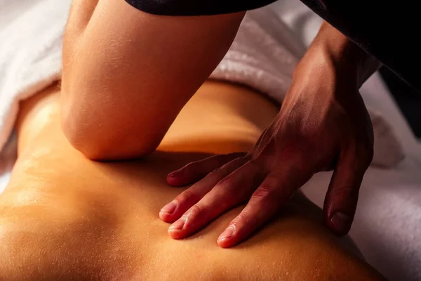 Masör elleri kaplıca merkezindeki kadın müşteriye sırt masajı yapıyor.