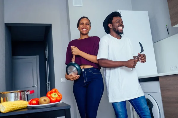 Beautiful young Afro American couple is smiling while dancing in kitchen