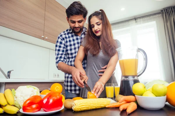 Mujer india feliz y hombre guapo mezclando frutas para batido fresco en luz de día brillante acogedora cocina — Foto de Stock