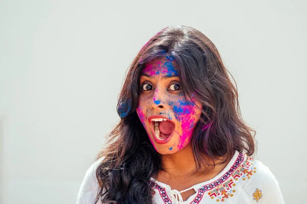 Festival Holi de Colores. Retrato de chica india feliz en color holi. ella bailando y divirtiéndose en fondo de estudio de pared blanca —  Fotos de Stock