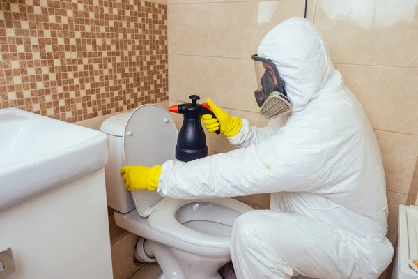 Disinfestatore spruzzando pesticidi con spruzzatore in bagno: lavorazione della toilette e della doccia — Foto Stock