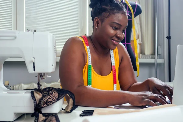 Жінка дизайнер моди з афро-косичками дредлоки, що працюють на її будинку в ательє — стокове фото