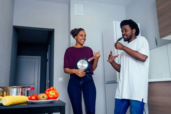 Hermosa pareja afroamericana joven está sonriendo mientras baila en la cocina — Foto de Stock