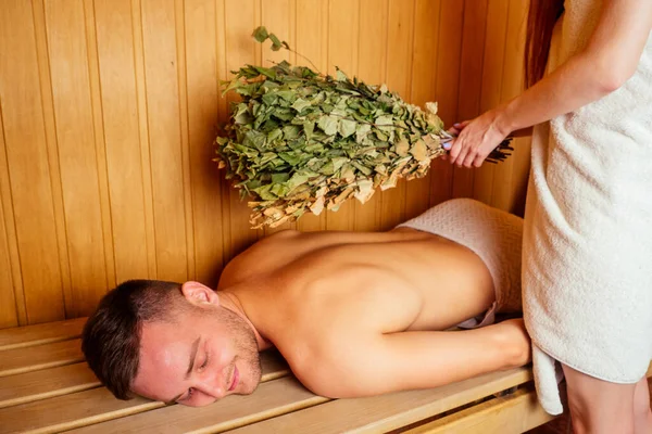 Pelirroja pelirroja mujer y su novio humeante en la casa de baños con el grupo ruso broom.couple en el amor disfrutando de la sauna juntos en el spa — Foto de Stock