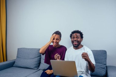 Evlerinde dizüstü bilgisayar kullanan mutlu bir çiftin portresi.