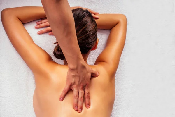 Mujer acostada en la mesa y recibiendo masaje ayurvédico con aceite orgánico o meleyed en cuarto oscuro. Masajista haciendo masaje de yoga — Foto de Stock