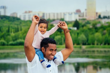 Afro babası melez kızına sarılıp bahçede vakit geçiriyor.