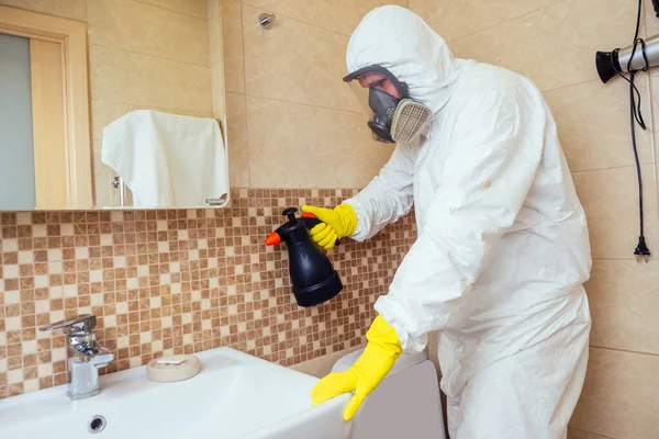 Trabalhador de controle de pragas pulverizando pesticidas com pulverizador no banheiro: processando o banheiro e chuveiro — Fotografia de Stock