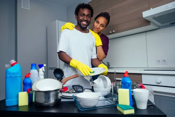 Giovane felice coppia afro-americana sta lavando i piatti mentre fa pulizia a casa — Foto Stock