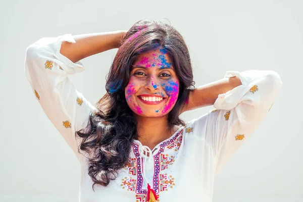 Festival Holi de Colores. Retrato de chica india feliz en color holi. ella bailando y divirtiéndose en fondo de estudio de pared blanca —  Fotos de Stock