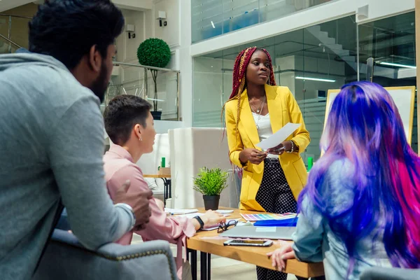 Kreatív ügynökség tervező csapat dolgozik együtt: afro-amerikai nő raszta copfos és kaukázusi lány rózsaszín kék többszínű haj kommunikáció indiai férfi az irodában — Stock Fotó