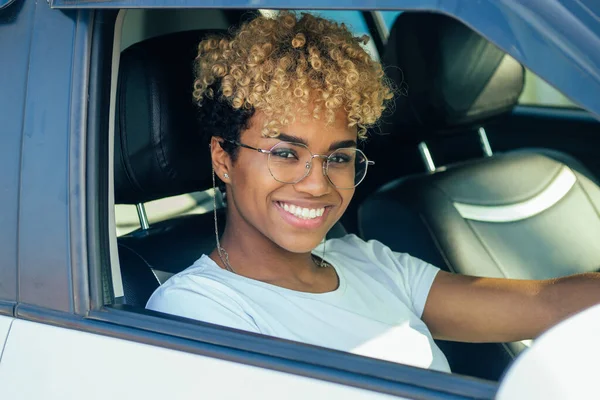 cheerful young african american latin girl showing her new car key at dealership