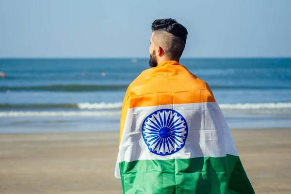 Индийский юноша размахивает индийским триколором под открытым небом рядом с пляжем, концептуальное изображение Дня Республики или Дня независимости — стоковое фото