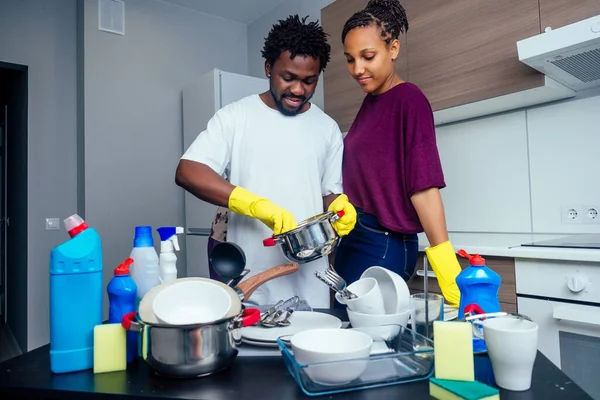 Giovane felice coppia afro-americana sta lavando i piatti mentre fa pulizia a casa — Foto Stock