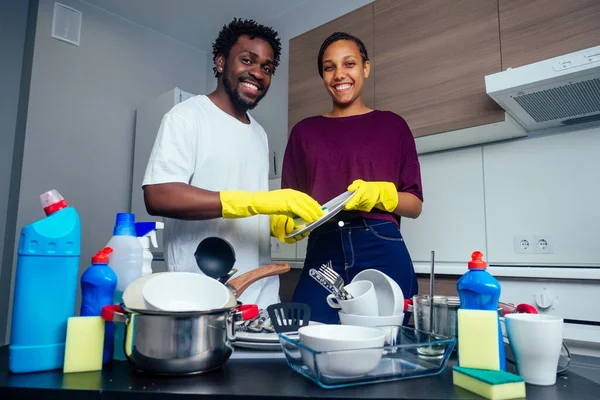 Joven pareja afroamericana feliz está lavando platos mientras hace la limpieza en casa — Foto de Stock
