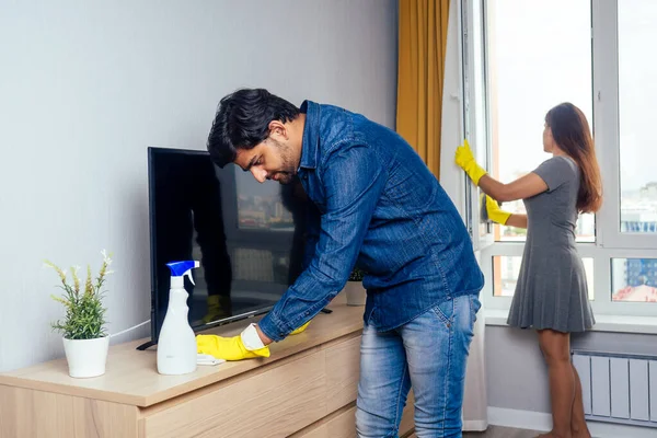 Νεαρό ζευγάρι ινδική κινείται στο νέο σπίτι, τον καθαρισμό και το ξεπακετάρισμα μεγάλο παράθυρο με κομψό κίτρινο φόντο κουρτίνα — Φωτογραφία Αρχείου
