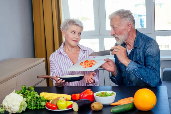 Senior couple preparing vegan dinner with organic fruits and vegatables