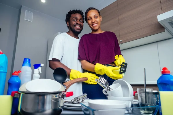 Joven pareja afroamericana feliz está lavando platos mientras hace la limpieza en casa — Foto de Stock