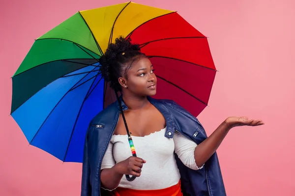 beautiful female in leather jacket standing under umbrella and holding phone weather app studio pink background