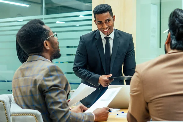 Hombres afro-americanos bien vestidos de negocios haciendo un informe a empleados subordinados en una oficina moderna — Foto de Stock