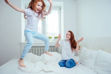 Anne ve kız evdeki yatakta zıplıyorlar. başarı kavramı