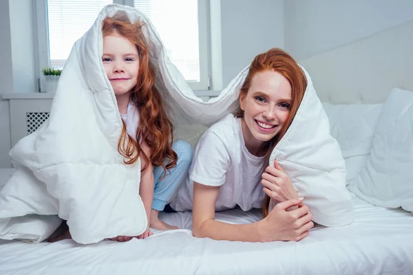 Dwa szczęśliwy rudowłosy rude dziewczyny zabawy w chowanego pod białym kocem — Zdjęcie stockowe