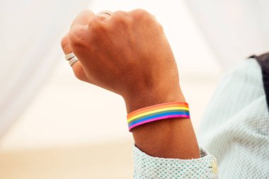 Siyah takım elbiseli Afro-Amerikan kadın damat ve mutlu Kafkas sarışın gelin birlikte kumsal töreninde çiçek kemerinin altında sevişiyorlar.