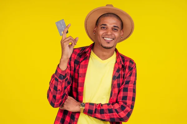 Афро-бразильский мужчина с кредитной картой в стусио на желтом фоне. — стоковое фото