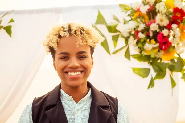 Marié américain africain en costume noir et mariée caucasienne en robe dans la cérémonie sur la plage tropicale sous voûte flottante de mariage — Photo