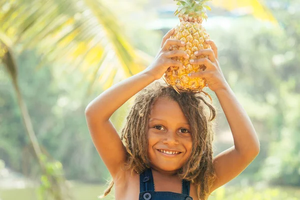 Маугли индийский мальчик с дредами волосы скрываются держа ананас в тропиках зеленый фон леса — стоковое фото