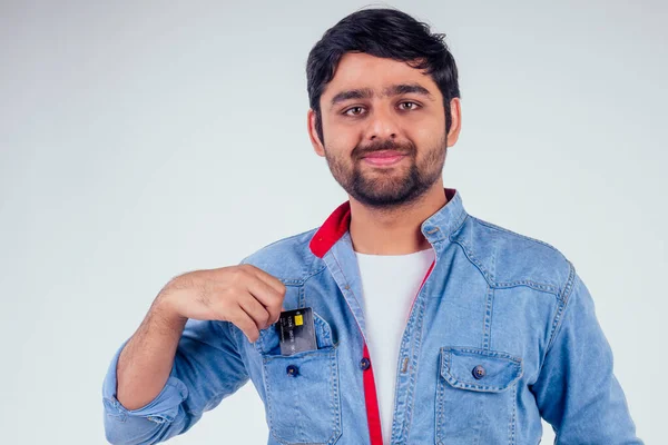 Feliz indio macho poner tarjeta de crédito en bolsillo en estudio blanco fondo — Foto de Stock