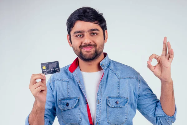 Šťastný indický muž držící kreditní kartu ve studiu bílé pozadí — Stock fotografie