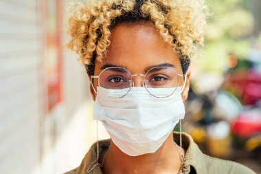 Koruyucu maskeli Afro kadın sokakta duruyor. Coronavirus konsepti
