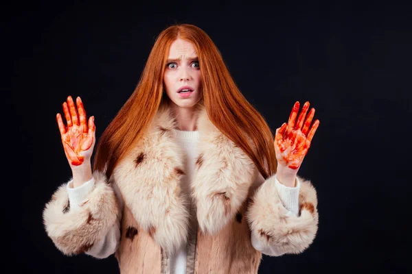 Θλιβερή κοκκινομάλλα γυναίκα θύμα μόδας τζίντζερ με αίμα στα χέρια της φορώντας φυσική γούνα παλτό και κλάμα, στούντιο μαύρο φόντο.Σταματήστε τη θανάτωση των ζώων παρακαλώ — Φωτογραφία Αρχείου