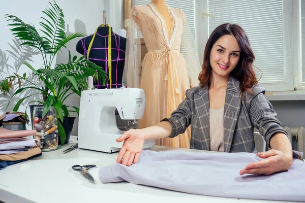 Retrato de uma costureira em uma jaqueta quadriculada trabalhando em seu estúdio de costura, ela mostrando dentro de forro de roupas — Fotografia de Stock