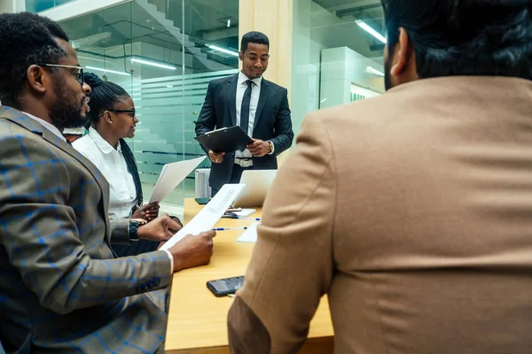 Hombres afro-americanos bien vestidos de negocios haciendo un informe a empleados subordinados en una oficina moderna . —  Fotos de Stock